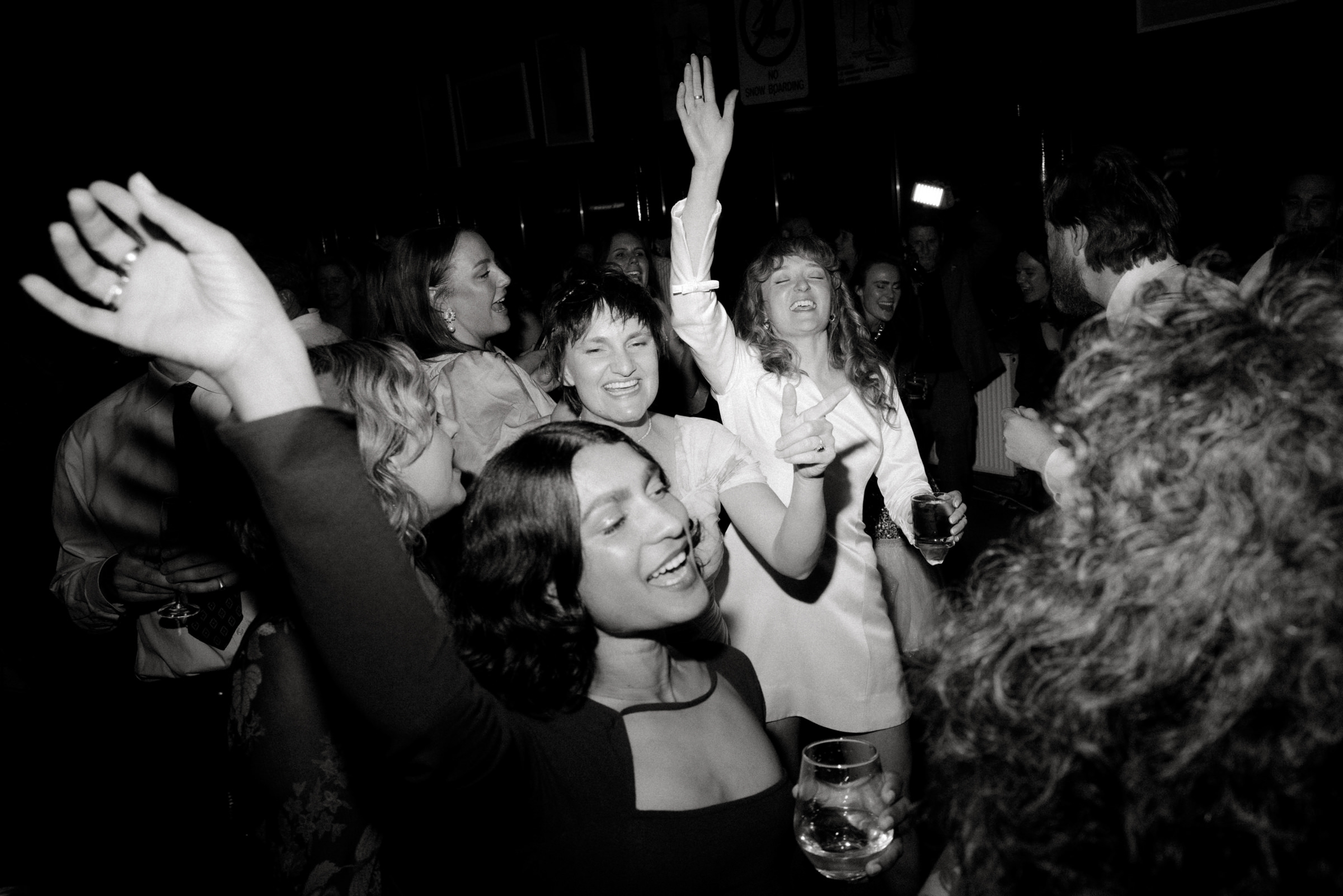 a black and white photo of guests dancing at the reception