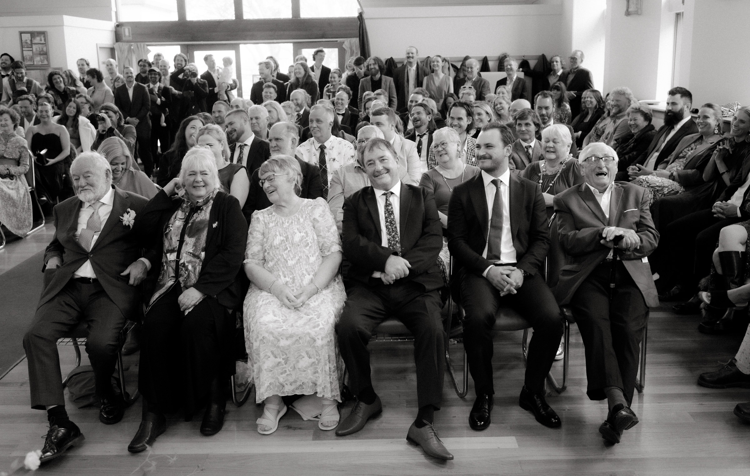 a black and white photo of the wedding congregation enjoying the wedding ceremony