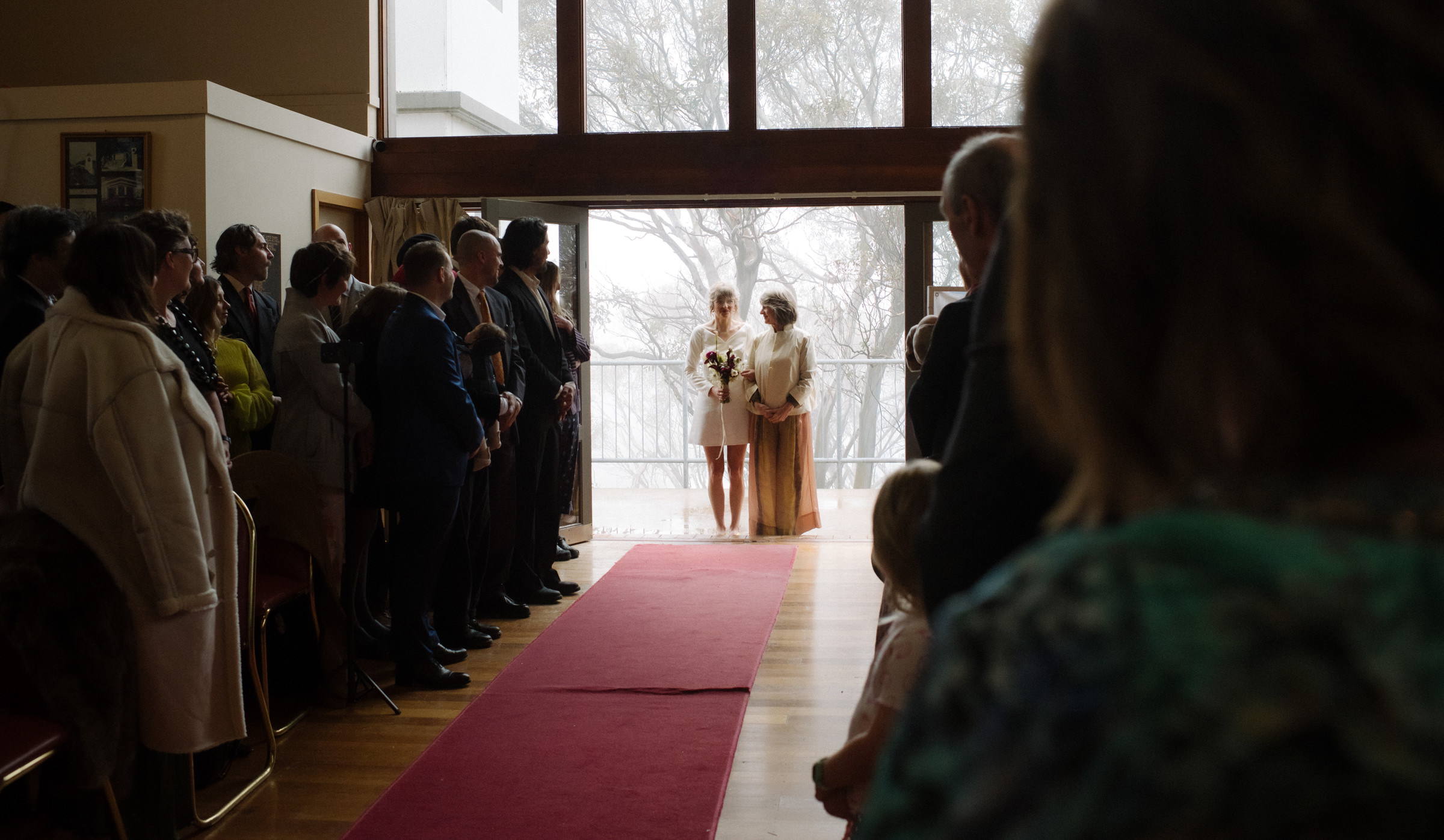the bride and her mother enter the chapel with misty mountain cloud behind them