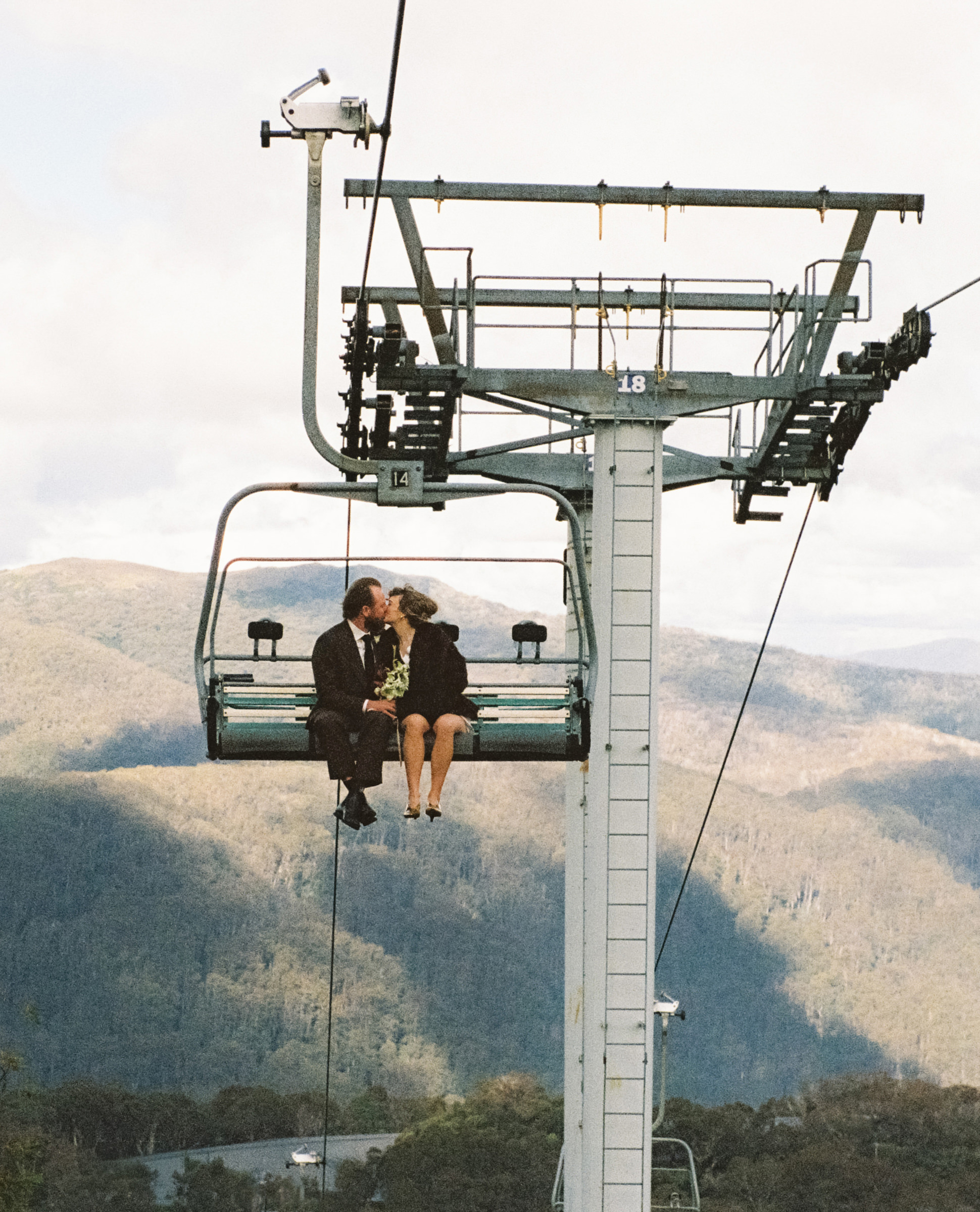 a couple share a kiss on the chairlift on their way to their wedding reception